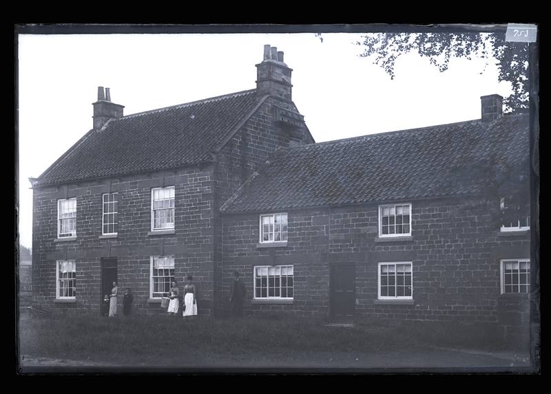 Two unidentified brick houses, with families outside, c.1900