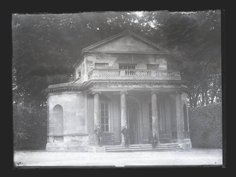 Three men outside a small stone summer house or folly, c.1900